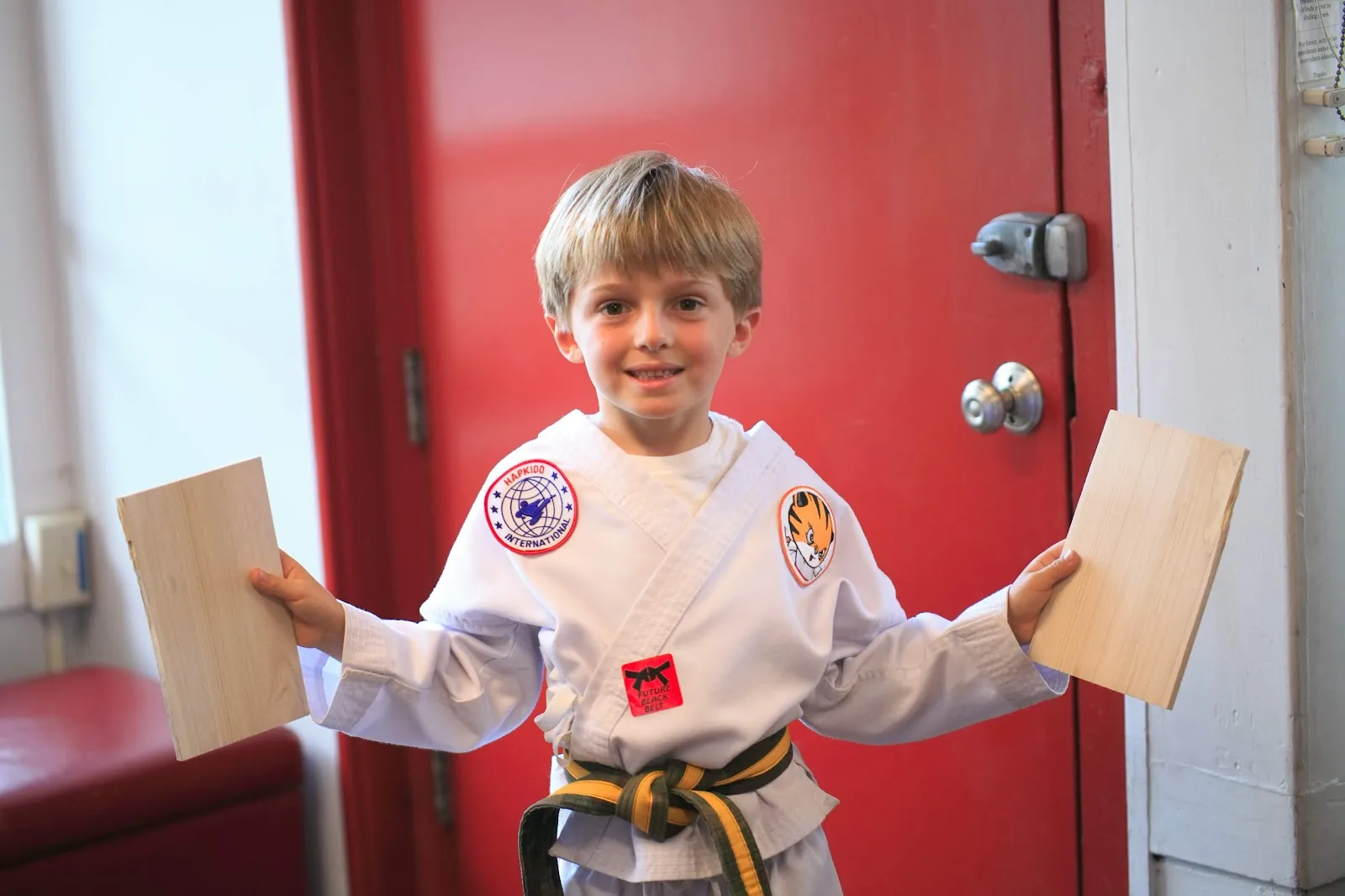 A child in a white uniform holds a kick while an instructor watches at Santa Barbara Dojo