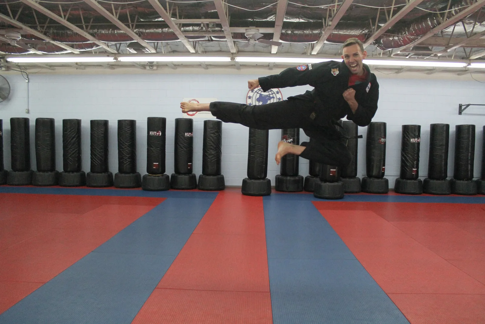An instructor demonstrating a jumping kick on the indoor dojo mat