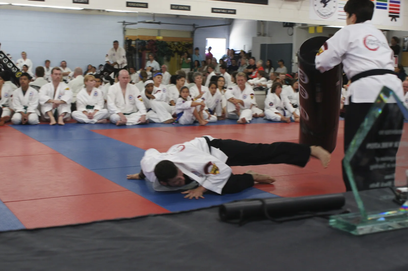 A student is thrown to the mat during the black belt demonstration as students watch