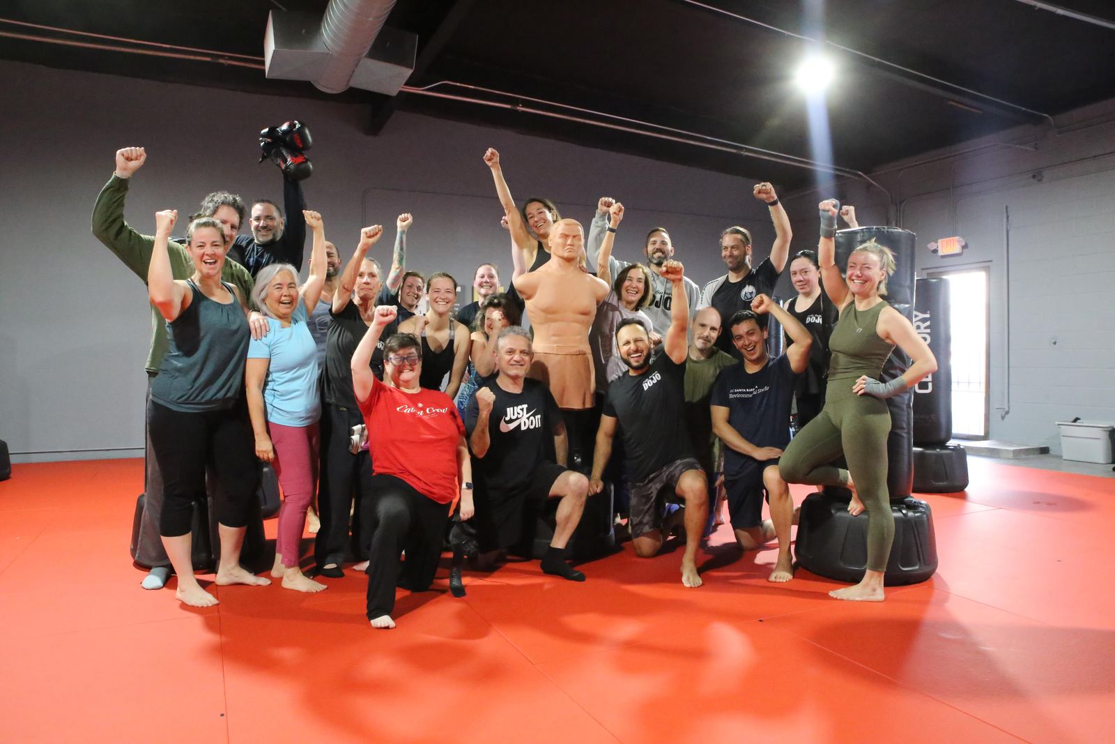 Adults punching heavy bags together in a coached kickboxing class at Santa Barbara Dojo