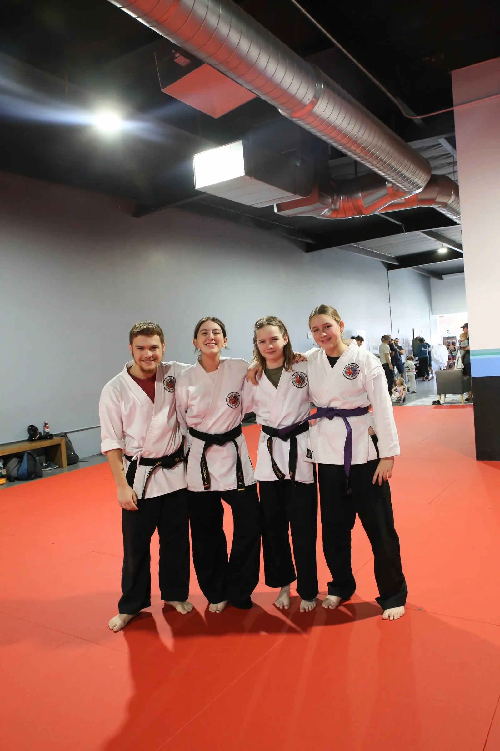 Three women wearing boxing gloves smile together at Santa Barbara Dojo