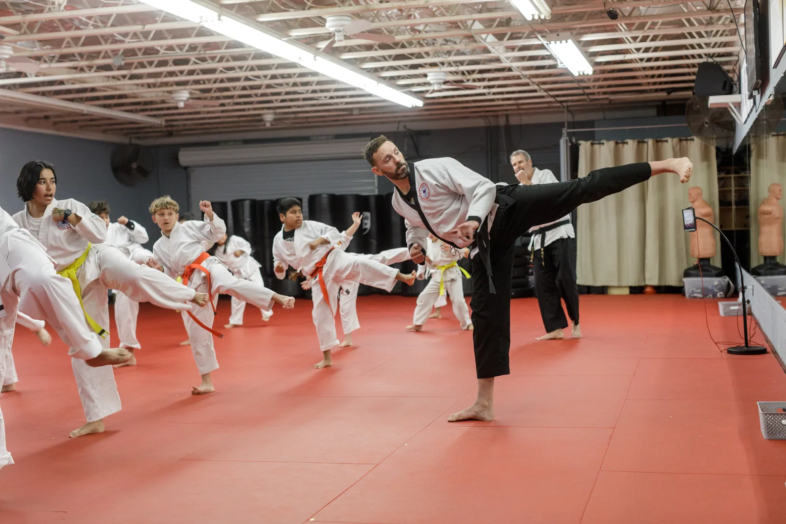 A line of children in uniform practice kicks together at Santa Barbara Dojo
