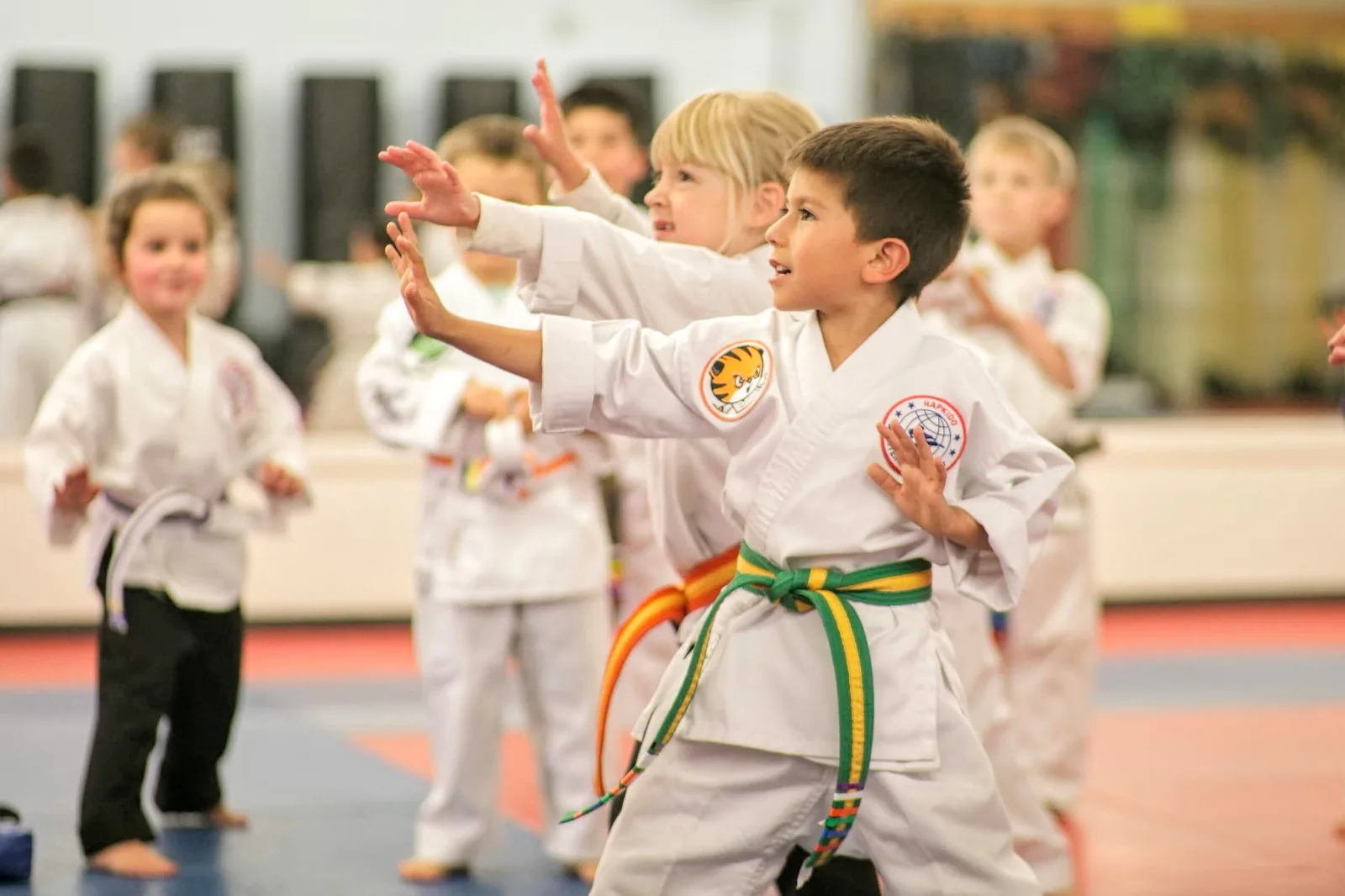 An instructor kneels with children in white uniforms during a kids martial arts class at Santa Barbara Dojo