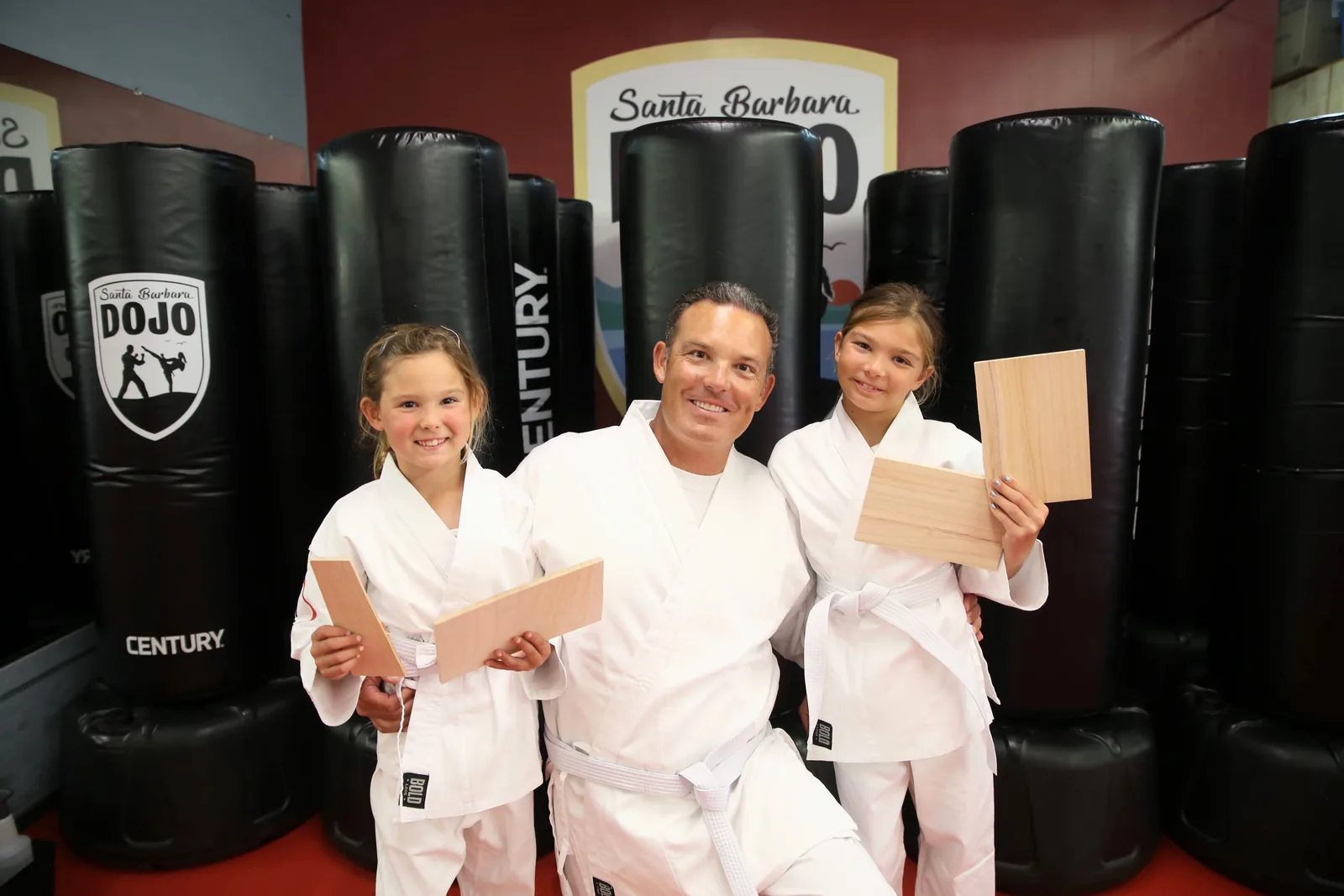An instructor presents a new belt to a student while the class watches at Santa Barbara Dojo