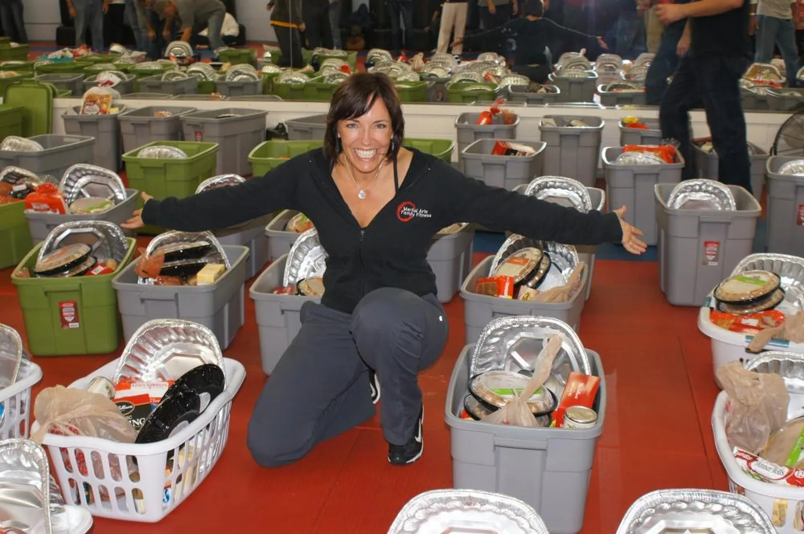 A volunteer kneeling among rows of packed Thanksgiving baskets at the Basket Brigade