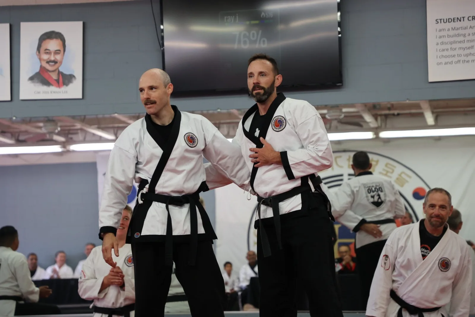Two black belt masters in uniform standing on the mat during a black belt event